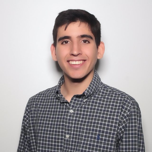 Jordon smiling in a plaid shirt against a light background