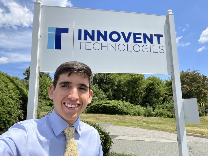 Jordon smiling in front of the Innovent Technologies sign on a sunny day