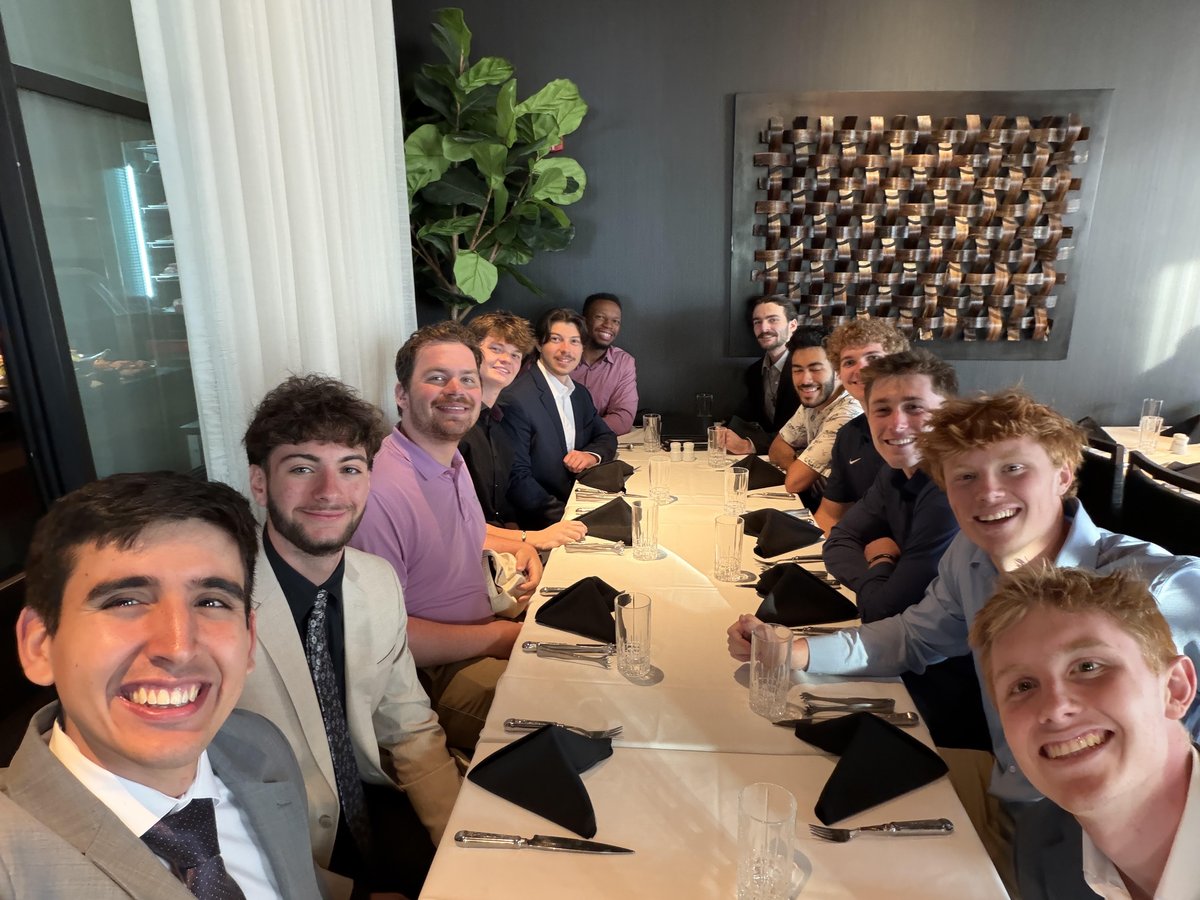 Jordon taking a smiling selfie with the men of his household around a long dinner table