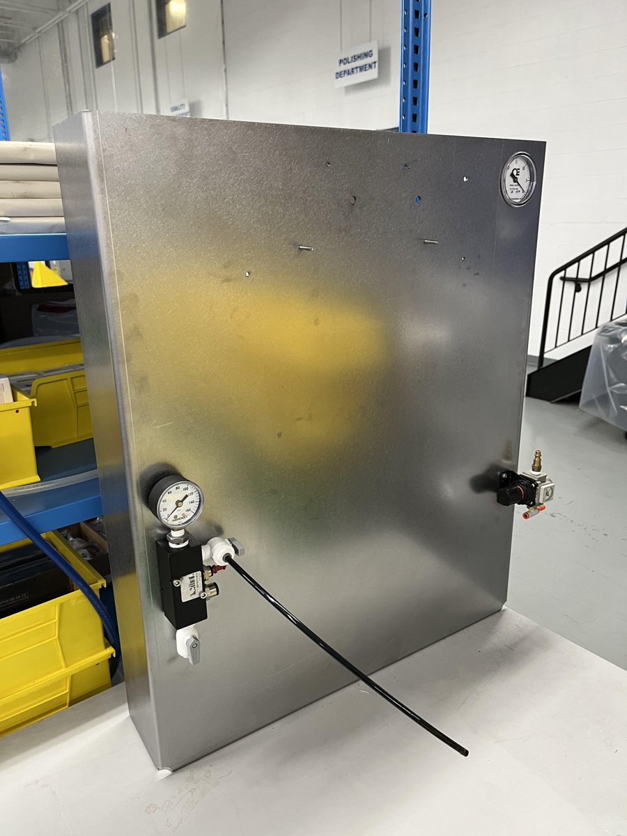 Sheet metal pneumatic test stand with a pressure gauge, valve block, regulator and vacuum gauge mounted on its face